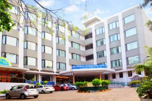 un gran edificio con coches estacionados frente a él en Ashraya International Hotel, en Bangalore