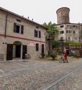 een man die met een fiets voor een gebouw loopt bij WineBikeHostel in Rocca Grimalda
