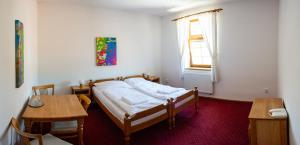 a bedroom with a bed and a table and a window at Grandhotel Sluchátko - EX Zámecký hotel in Vranov nad Dyjí