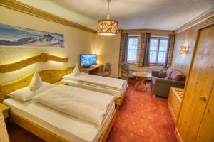 a hotel room with two beds and a desk at Gasthof Alt Paznaun in Ischgl
