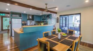 a kitchen and dining room with a wooden table and chairs at Airlie Guest House in Airlie Beach