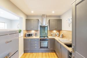 a kitchen with gray cabinets and a stove top oven at Thistle Lodge 21 with Hot Tub in Belladrum