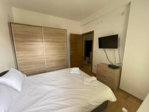 a bedroom with a white bed and a flat screen tv at Duga in Kragujevac