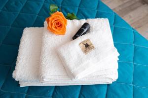 biały ręcznik z długopisem i pomarańczową różą w obiekcie Charissa apartment w mieście Wolos