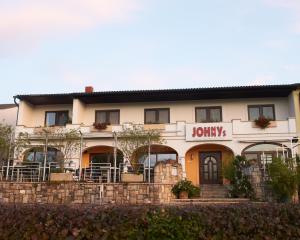 ein Gebäude mit einem Schild, das Johannys liest in der Unterkunft Gästehaus Weinhandl & Johnnys Pizzeria in Podersdorf am See