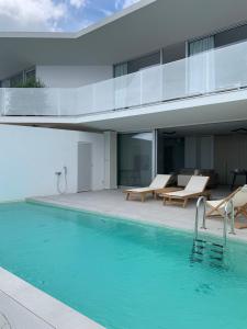 a swimming pool with two chairs and a building at Vila Villaarh in Krk