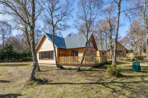 a small wooden house in the middle of trees at Thistle Lodge 21 with Hot Tub in Belladrum