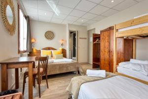 a bedroom with two beds and a table and a desk at H&ocirc;tel Les Essarts, USSIM Vacances in Valloire