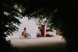 a woman riding a bike in front of a white building at Keenaghan Cottage Belleek Fermanagh Northern Ireland in Belleek