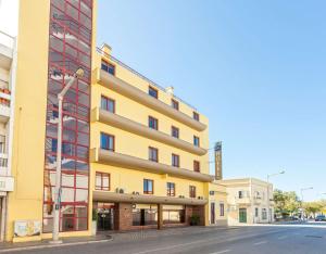 un edificio amarillo al costado de una calle en Best Western Hotel Dom Bernardo, en Faro