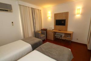 a hotel room with two beds and a television at Best Western Hotel Dom Bernardo in Faro