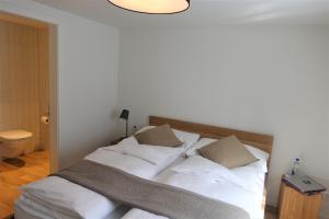 a bedroom with a bed with white sheets and pillows at Hotel Bären Guttannen in Guttannen