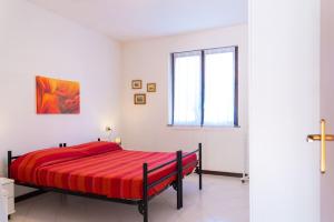 a bedroom with a red bed in a white room at Appartamento Le Ginestre - IC Immobiliare in Rio nellʼElba
