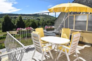 a table and chairs with a yellow umbrella on a balcony at Apartment Moselblick in Ürzig