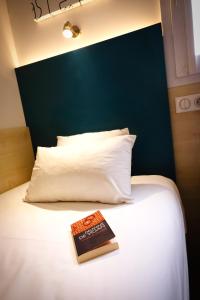 un libro sobre una cama blanca en Kyriad Direct Perpignan - Aeroport, en Rivesaltes