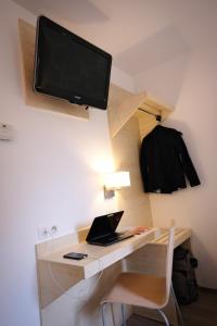 a desk with a laptop and a tv on a wall at Kyriad Direct Perpignan - Aeroport in Rivesaltes