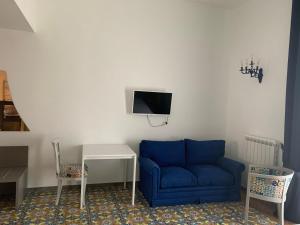 a living room with a blue couch and a tv on a wall at Specchio di Parthenope B&B in Naples