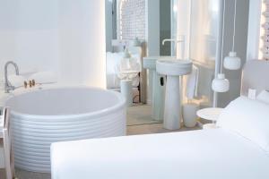 a white bathroom with a tub and a sink at Hotel Faro Lariño in Lariño