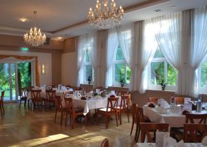 a dining room with tables and chairs and chandeliers at Parkhotel Altes Kaffeehaus in Wolfenbüttel