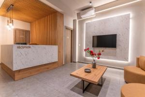 AURA APARTMENTS في كيراموتي: غرفة معيشة مع طاولة وتلفزيون على الحائط