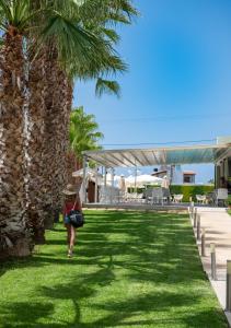 a woman walking in the grass near a palm tree at Angela Suites Boutique Hotel in Sissi