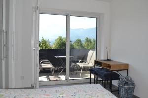 a bedroom with a bed and a balcony with a table and chairs at Apartment Uggowitzer in Drobollach am Faaker See