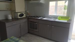una cucina con lavello e fornello forno superiore di Mobile-home a Braucourt