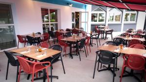 un restaurant vide avec des tables et des chaises en bois dans l'établissement Kyriad Direct Perpignan - Aeroport, à Rivesaltes