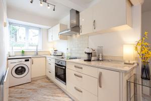 cocina con armarios blancos, lavadora y secadora en Cosy 2 Bed Apartment - Close to Leeds Centre, en Moortown