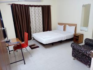 Habitación con cama, silla y sofá en Hotel Relax Inn, en Nagpur