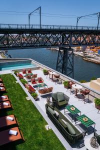 a group of tables and chairs on a patio with a bridge at Vincci Ponte de Ferro in Vila Nova de Gaia