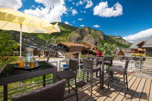 un patio con mesas y sillas con montañas en el fondo en Hôtel Les Essarts, USSIM Vacances, en Valloire