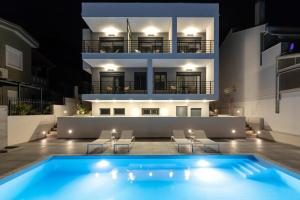 a swimming pool in front of a building at night at Cove Suites in Iraklitsa