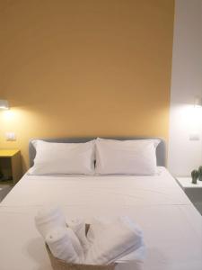 a bed with white pillows and a basket of towels at ISTAI Cagliari City Center Rooms in Cagliari