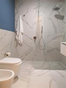 a white bathroom with a toilet and a shower at ISTAI Cagliari City Center Rooms in Cagliari