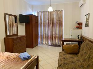 a living room with a couch and a television and a desk at Uyut Guest House in Koktebel