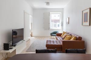 ein Wohnzimmer mit einem Sofa und einem TV in der Unterkunft Classy 2BDR Apartment in Downtown by LovelyStay in Lissabon