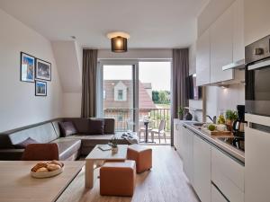 a kitchen and living room with a couch and a table at Holiday Suites Jabbeke - Klein Strand in Jabbeke