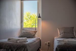 Habitación con 2 camas, ventana y lámpara. en Ravinstigen - Visby Lägenhetshotell, en Visby