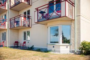 Ravinstigen - Visby Lägenhetshotell في فيسبي: مبنى عليه شرفات حمراء وكراسي حمراء