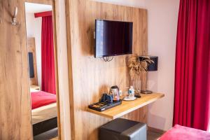 a room with a mirror and a television on a wall at Hotel Am Siebersturm in Rothenburg ob der Tauber
