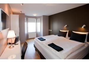 1 dormitorio con 1 cama grande y 2 toallas negras. en Torg Guest House en Akureyri