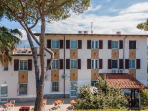 a large white building with windows and a tree at Hotel Villa Giada in Marina di Massa