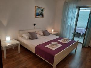 a bedroom with a large white bed and a table at Apartments and Rooms Vinko in Barbat na Rabu