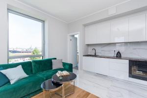 a living room with a green couch and a kitchen at Yacht Park Rentyear Apartments in Gdynia