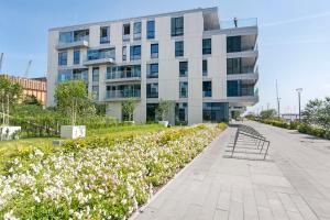 a building with a garden of flowers in front of it at Yacht Park Rentyear Apartments in Gdynia