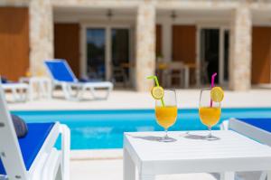 two drinks on a table next to a pool at Villa Zala in Rasopasno
