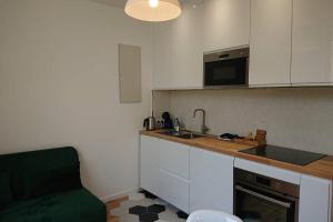 a kitchen with white cabinets and a green couch at T2 calme et design quartier Chartrons à Bordeaux in Bordeaux