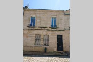 um edifício de pedra com janelas azuis e uma porta em T2 calme et design quartier Chartrons à Bordeaux em Bordéus