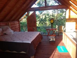 1 dormitorio en una cabaña de madera con 1 cama y 1 mesa en Cabaña Arrayanes, en Rionegro